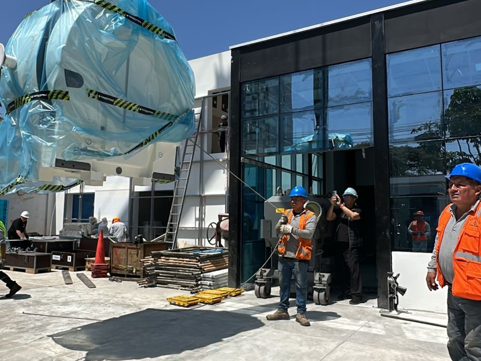 Izaje de la unidad de radiación hacia el interior del predio. La operación requirió una grúa de 30 toneladas y coordinación milimétrica con el personal técnico del fabricante para el ingreso por la apertura del edificio.
