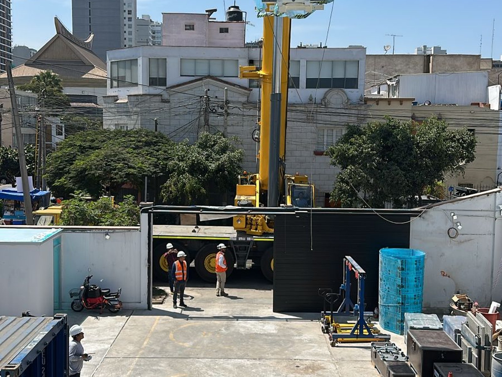 Vista general del izaje desde el segundo nivel. Se aprecia la grúa de 30 toneladas posicionada en la vía colindante, la unidad en suspensión y el estacionamiento interior operando como zona de acopio de los componentes del equipo.