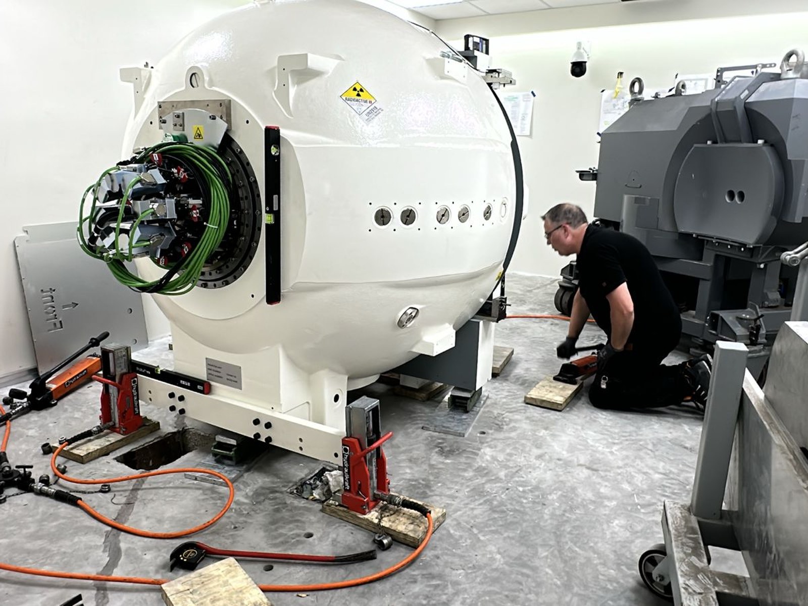 Fase de montaje: la unidad de radiación ya posicionada en la losa de 65 cm y el robot de instalación en proceso de acoplamiento. Los gatos hidráulicos en primer plano garantizan la nivelación precisa del sistema.