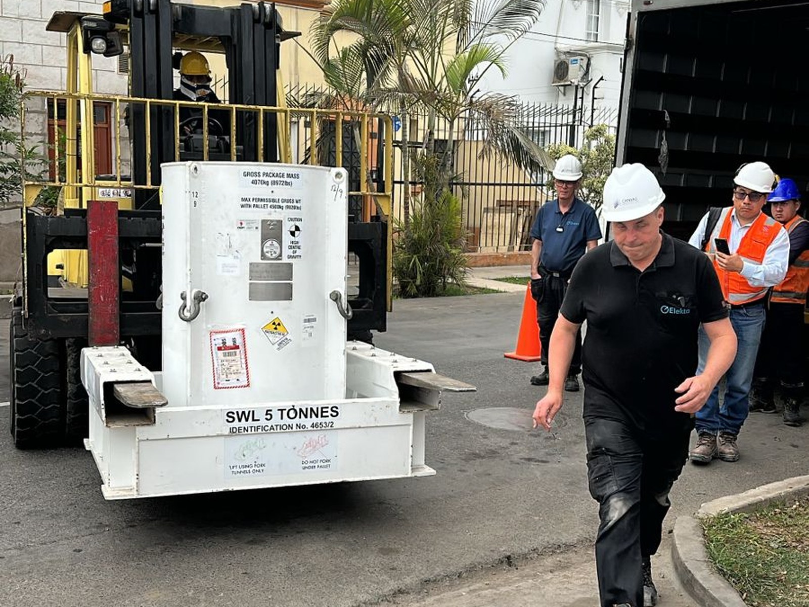 Un técnico de Elekta escoltando el traslado del contenedor de fuentes radiactivas en la vía pública mediante montacargas. La operación requirió coordinación previa con las autoridades de tránsito y permisos específicos del IPEN para el traslado de material radiactivo.