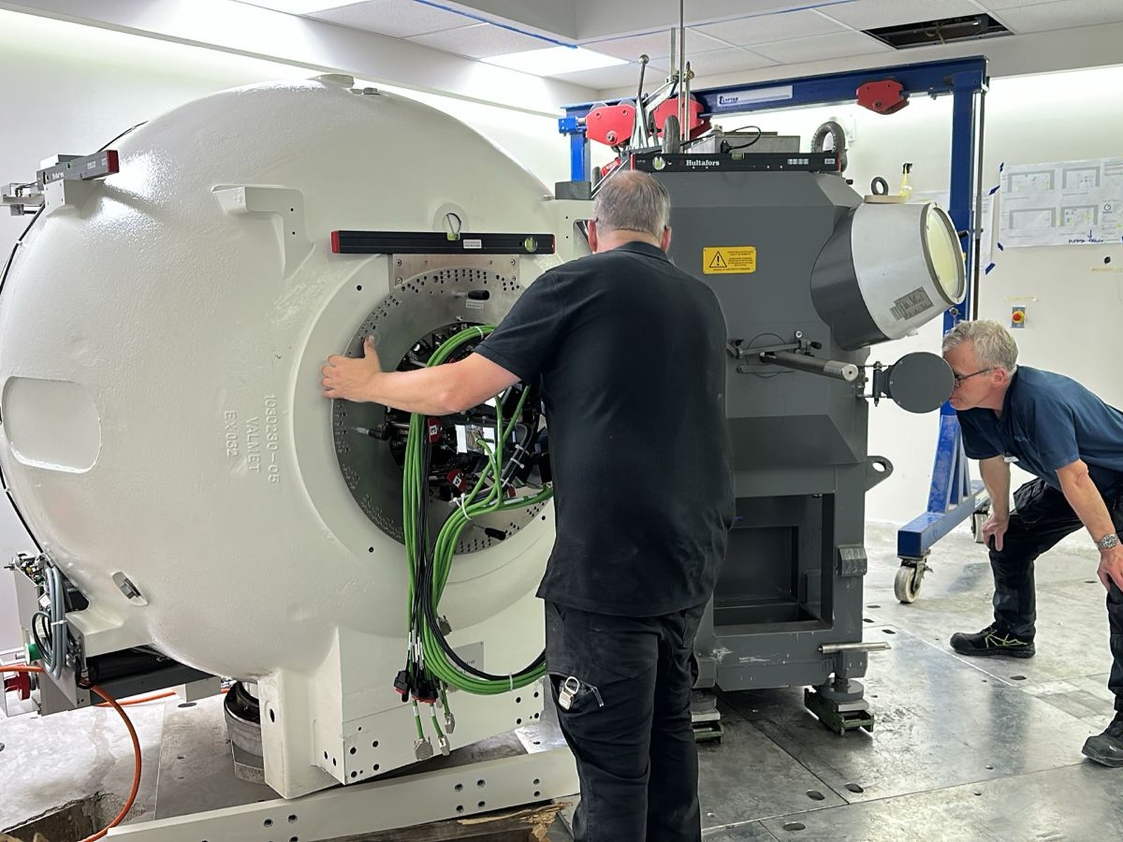Contenedor de fuentes radiactivas ingresando al búnker a través del corredor interior. Al fondo, la unidad de radiación del Gamma Knife Esprit ya posicionada sobre la losa de 65 cm aguarda la carga de las semillas radiactivas.